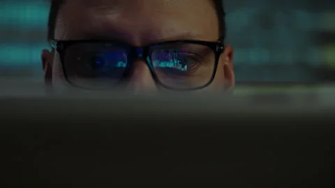 Reflection in the programmers glasses. At night, an IT worker with a portabl Stock Footage 323929976