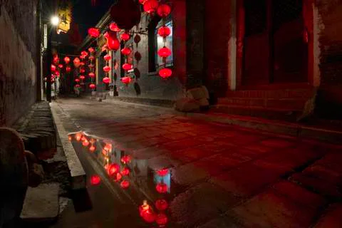 Reflection in puddle of Red lanterns and bokeh at night in a street in Pingyao Foto stock
