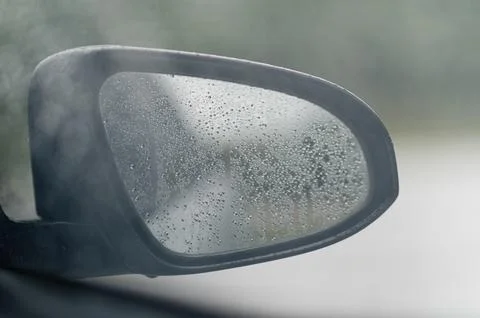 Reflection in Rainy Car Mirror with Blurred Green Background Stock Photos