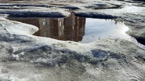 Reflection of a residential building in a puddle of melting snow Stock Footage 330405547