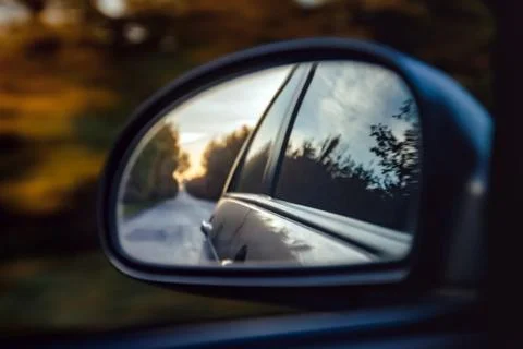 Reflection of the road in the sunset sunlight blurry in the side mirror of th Stock Photos