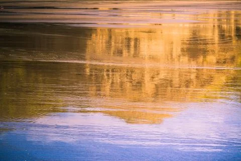 Reflection of rock formations and bright blue sky in wet surface of sandy beach. Stock Photos