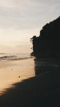 Reflection of a rock hill on the beach during sunset 库存照片