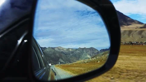 Reflection of rugged mountains and clear sky in car mirror Stock Footage 342734479
