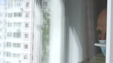 Reflection of sad old man in mask waving hand at window Stock-Footage 134998275