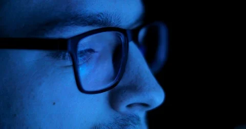 Reflection of the screen in the man's glasses in the dark. Vídeo Stock 105303414