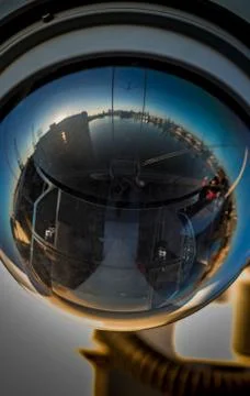 Reflection in a security camera of man standing on a dock with buildings arou Stock Photos
