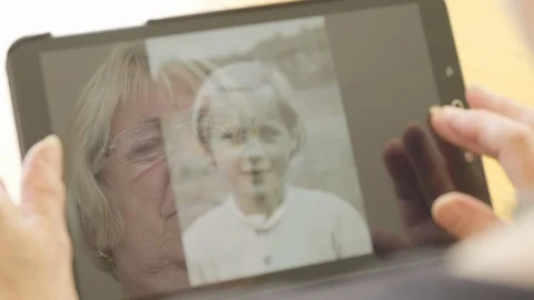Reflection of a senior woman looking at old photos on a tablet computer Video stock 92857553