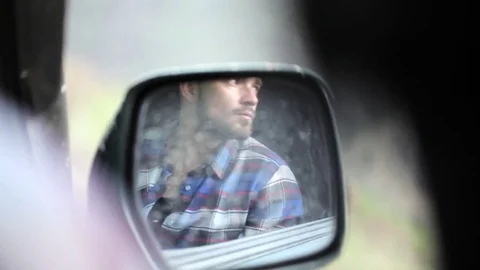 Reflection in side mirror of man sitting inside car and photographing Stock Footage 76050640