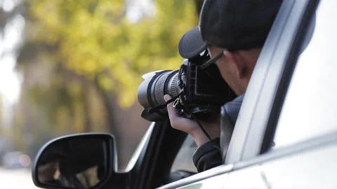 Reflection in side mirror of young private detective man sitting inside car and Stock Footage 98458006
