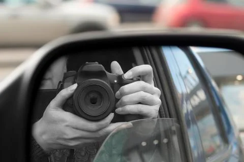 Reflection in side view mirror of someone with DSLR camera Stock Photos