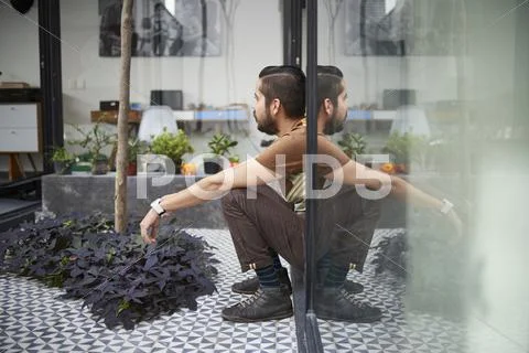 Reflection of sitting Hispanic man in atrium window Stock Photos