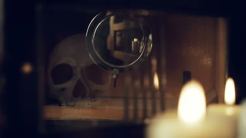 Reflection of the skull and candles in the pendulum of an old clock Stock Footage 97864171