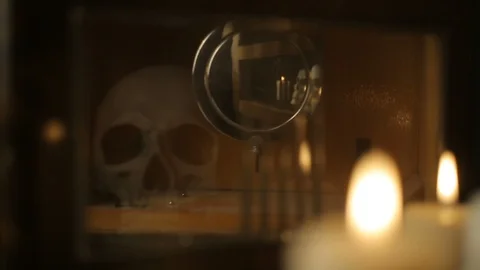 Reflection of the skull and candles in the pendulum of an old clock Stock Footage 108171157
