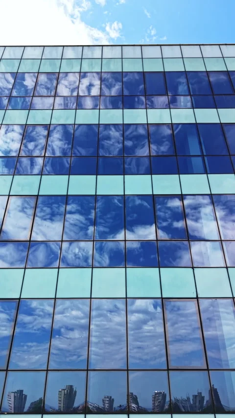 Reflection of sky and clouds on glass building in urban area during daytime Stock Footage 337912002
