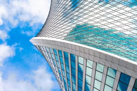 Reflection of sky and clouds in glass spiral, wave with bend facade windows o Stock Photos