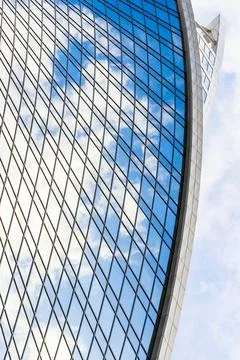 Reflection of sky and clouds in glass spiral, wave with bend facade windows o Stock Photos