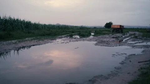Reflection of a sky and clouds on a puddle in front of a small wheelbarrow in Stock Footage 95620432