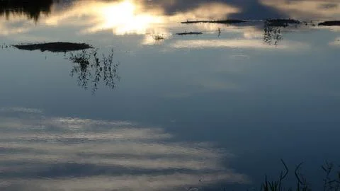 Reflection of the sky and clouds in the surface of the river on a dark evenin Stock Photos