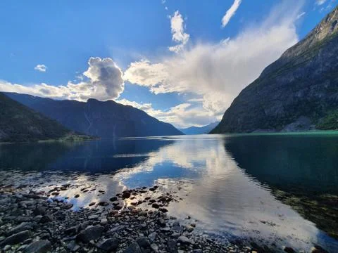 Reflection of the sky and mountains in the blue water Stock Photos
