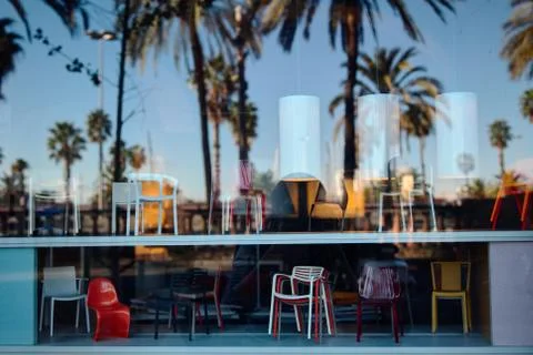 Reflection of the sky and palm trees in the window of a furniture store Stock Photos