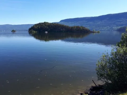 Reflection of sky and trees in the blue water Stock Photos