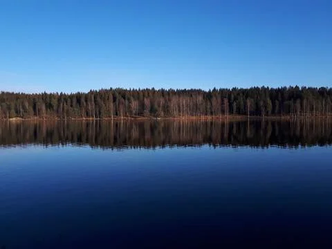 Reflection of the sky and trees in the blue water - Oslo, lake Sognsvann Stock Photos