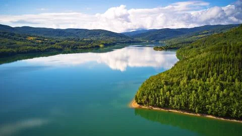 Reflection of sky, clouds, forest and mountains in water. Summer landscape wi Stock Photos