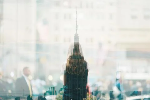 A reflection of a skyscraper and a woman's back in a storefront. Fotos Stock