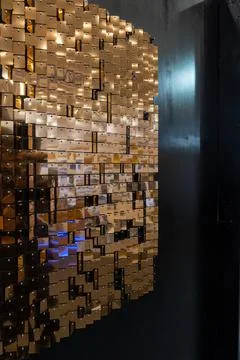 Reflection of small copper pieces on a black wall, reflecting people passing by Foto stock