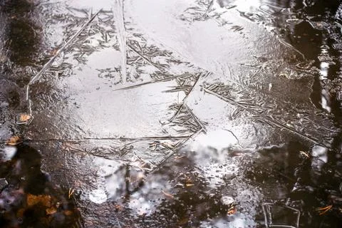 Reflection in splintered shards of ice in a puddle Stock Photos