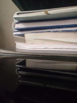 Reflection of a stack of notebooks on a glass table Stock Photos