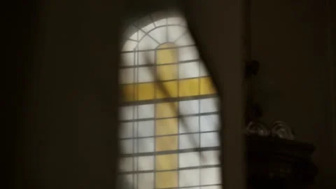 Reflection of a stained glass window of a yellow cross on a church window Stock Footage 132894768