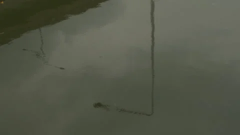Reflection of street lamp post on murky water surface with ripples. Stock Footage 323094834