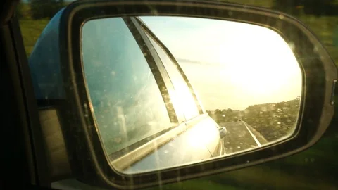 Reflection of summer sunset and road in the rear view mirror of the car Stock Footage 125690015