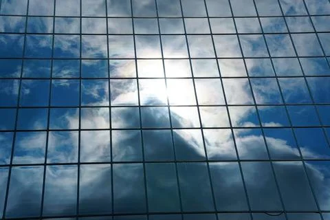 The reflection of the sun and clouds on the glass windows of a building, cr.. Fotos de archivo