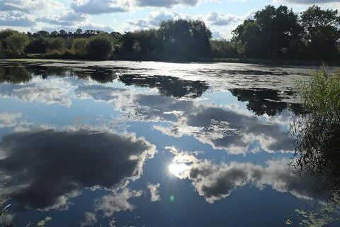 A reflection of the sun passing behind some black clouds on the River Exe nea 스톡 사진