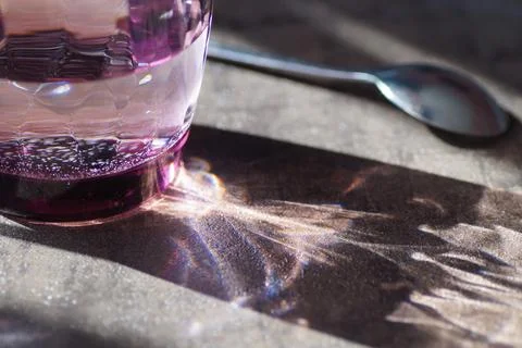 Reflection of sun rays on the table from a glass of water Stock Photos