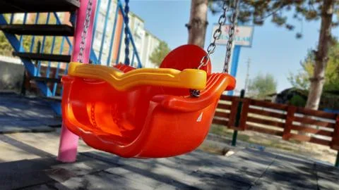 The reflection of the sun on the red swing in the park. Stock Photos