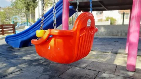 The reflection of the sun on the red swing in the park. Stock Photos