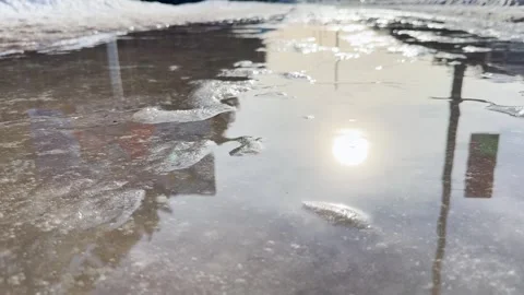 Reflection of sunlight in a melting puddle on a city street Video stock 330405593