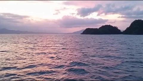 Reflection of sunset light on the ocean with a mountain island in the background Video stock 277922593