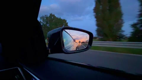 Reflection of the sunset in the rearview mirror of a car. Travel by car. Stock Footage 220222009