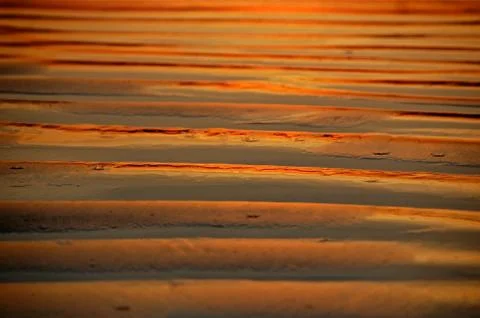 Reflection of sunset in sand waves red orange and metallic Stock Photos