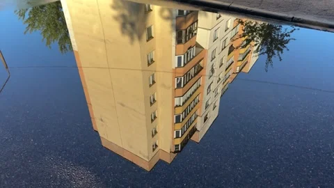 Reflection of a tall yellow apartment building in a rain puddle  Stock Footage 340515232
