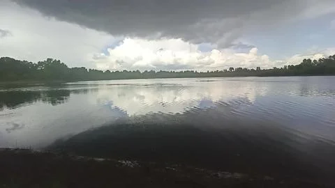 Reflection of thunderclouds in the shaky surface of a wide river with a wea.. Stock Photos