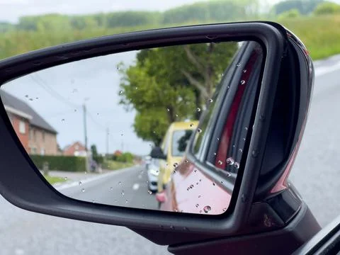 Reflection of traffic flow on the side mirror of a red car Stock Photos