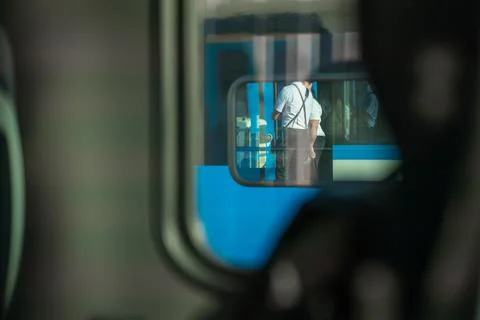A reflection in a train window shows uniformed railway staff standing outside on Stock Photos