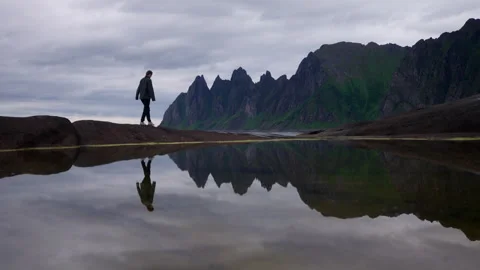 Reflection of traveler in pool of Devil's Teeth Okshornan mountain in Tungeneset Stock Footage 317542738