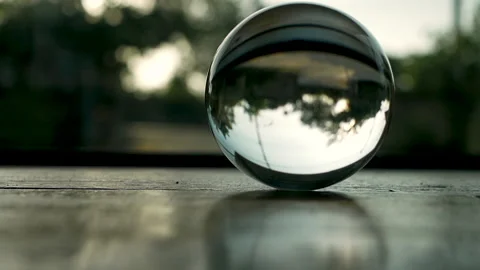Reflection of tree with environment in crystal glass ball on wooden table. Stock Footage 131953379